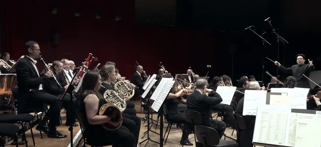 Sungwook Kim conducting, with the orchestra visible